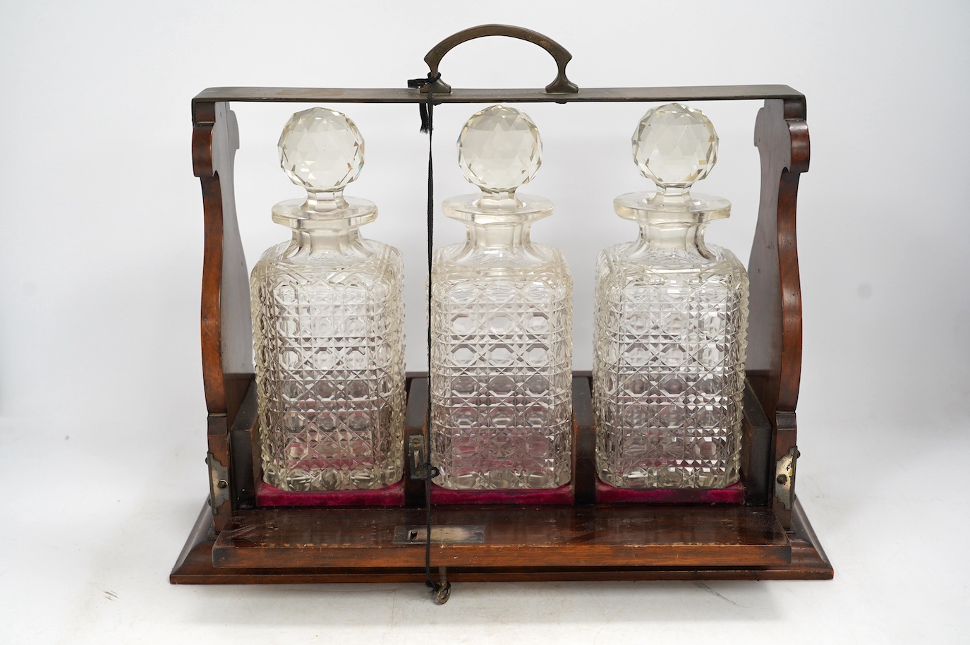 A three bottle tantalus with key, 38cm wide. Condition - fair, chipping to the stoppers